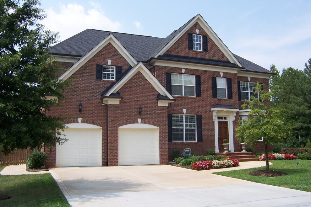 This is an example of a large traditional two-storey brick red exterior in Charlotte with a hip roof.