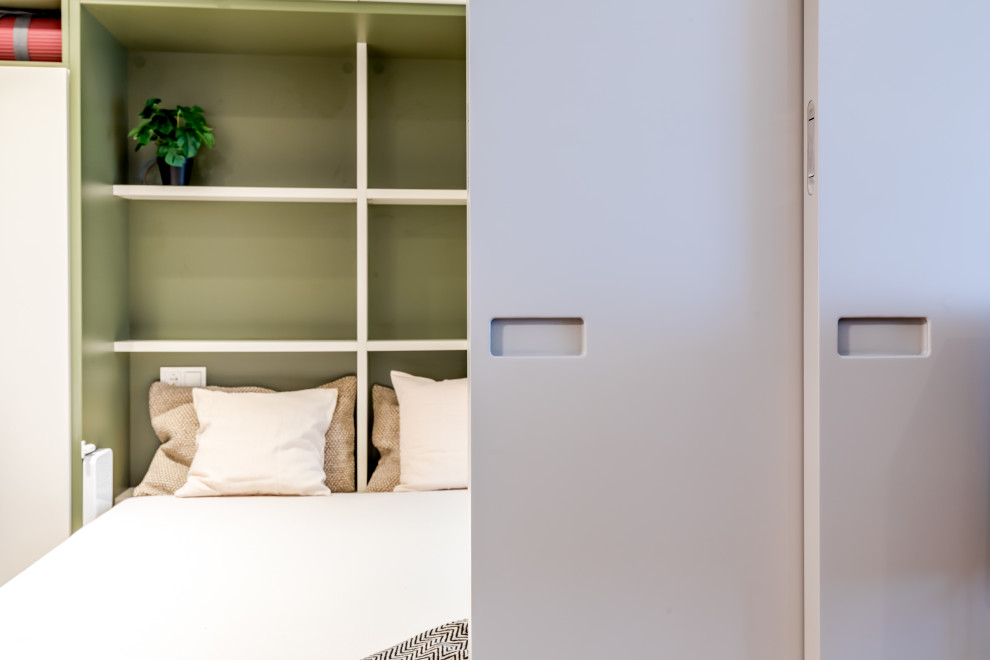 На фото: маленькая гостевая, серо-белая спальня (комната для гостей) в стиле лофт с белыми стенами, паркетным полом среднего тона, коричневым полом, балками на потолке и панелями на стенах для на участке и в саду