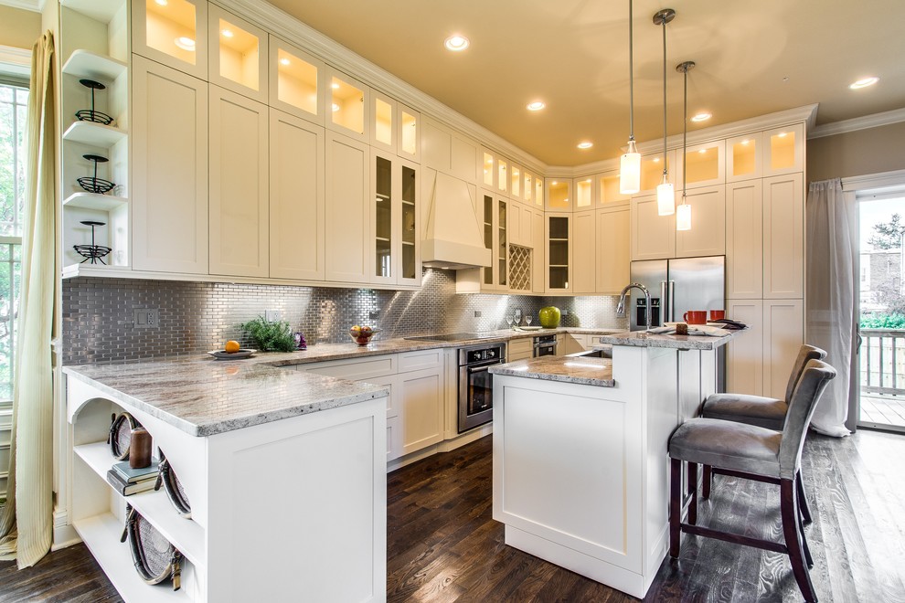 This is an example of a transitional u-shaped kitchen in Chicago with shaker cabinets, white cabinets, metallic splashback, metal splashback and stainless steel appliances.