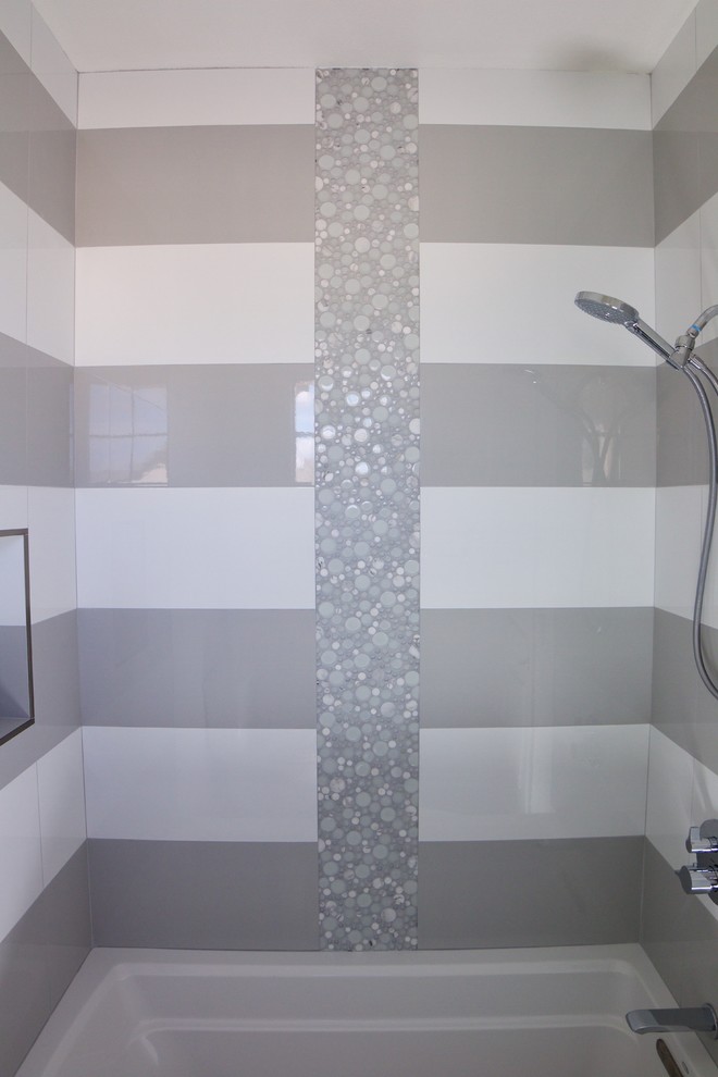 This is an example of a mid-sized modern 3/4 bathroom in Orange County with a drop-in tub, a shower/bathtub combo, gray tile, multi-coloured tile, white tile, porcelain tile, white walls and a shower curtain.