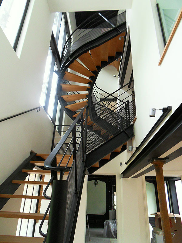 Design ideas for a large modern wood curved staircase in Paris with open risers and metal railing.