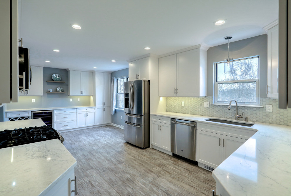 Example of a mid-sized transitional vinyl floor and gray floor eat-in kitchen design with an undermount sink, shaker cabinets, white cabinets, quartz countertops, gray backsplash, glass tile backsplash, stainless steel appliances, no island and white countertops