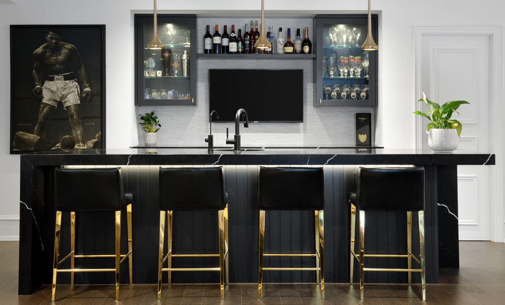 Design ideas for a transitional seated home bar in Toronto with glass-front cabinets, black cabinets, white splashback, brown floor and black benchtop.