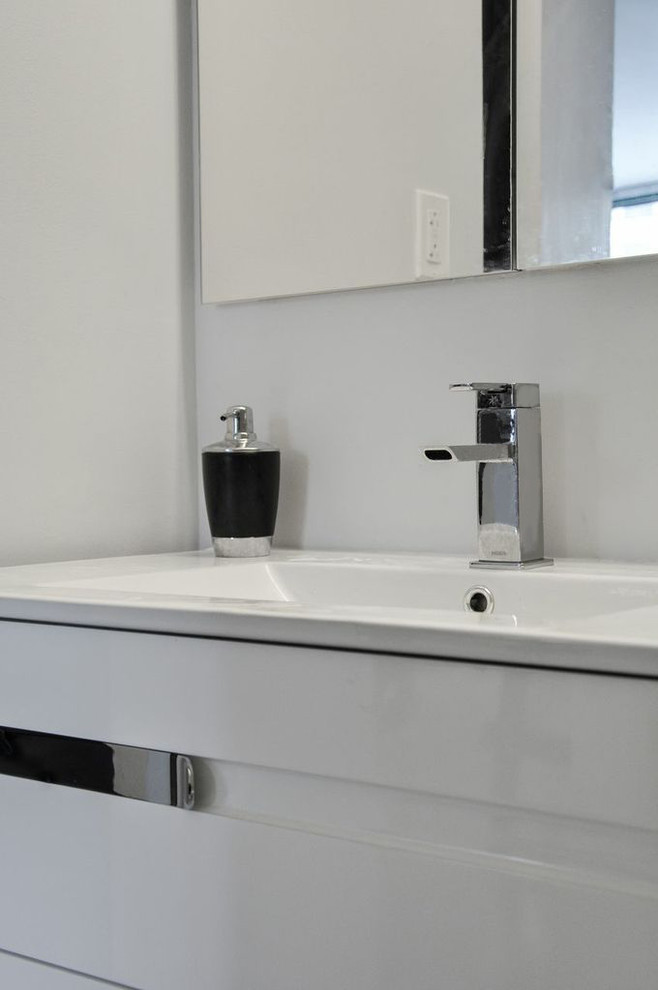 This is an example of a mid-sized contemporary bathroom in New York with an integrated sink, white cabinets, solid surface benchtops, an alcove tub, an alcove shower, a two-piece toilet, gray tile, grey walls and marble floors.