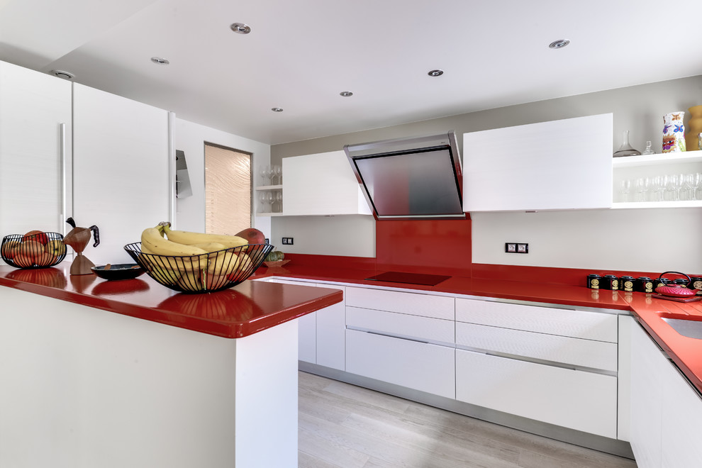 Photo of a mid-sized contemporary l-shaped separate kitchen in Paris with a single-bowl sink, flat-panel cabinets, white cabinets, red splashback, stainless steel appliances, light hardwood floors, no island, brown floor and red benchtop.