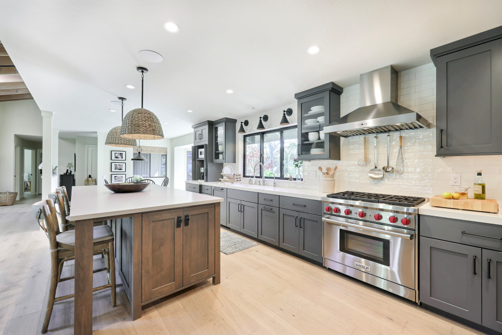 Open concept kitchen - mid-sized transitional l-shaped laminate floor open concept kitchen idea with a double-bowl sink, flat-panel cabinets, gray cabinets, quartz countertops, white backsplash, ceramic backsplash, stainless steel appliances, an island and white countertops