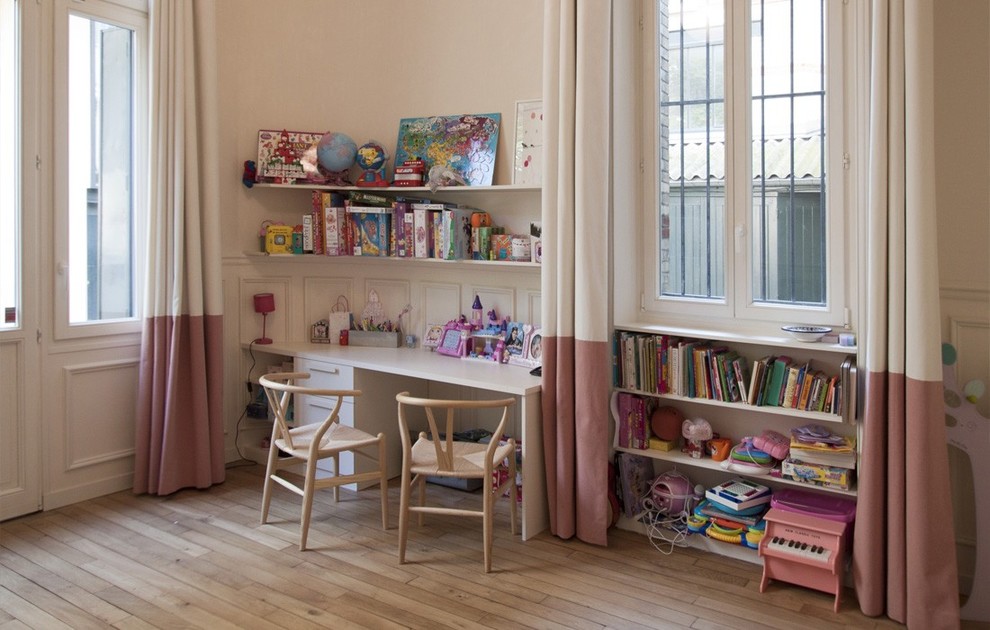 Photo of a transitional kids' study room for kids 4-10 years old and girls in Paris with beige walls and light hardwood floors.