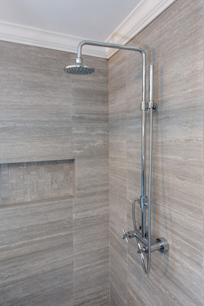 This is an example of a large transitional master bathroom in Philadelphia with furniture-like cabinets, dark wood cabinets, a freestanding tub, an alcove shower, beige tile, grey walls, ceramic floors, an undermount sink, marble benchtops, white floor, a hinged shower door and white benchtops.