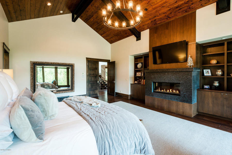 Large contemporary master bedroom in Salt Lake City with white walls, dark hardwood floors, a standard fireplace, a stone fireplace surround and brown floor.