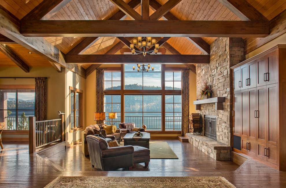 Country open concept living room in Other with dark hardwood floors, a standard fireplace, a stone fireplace surround and brown floor.