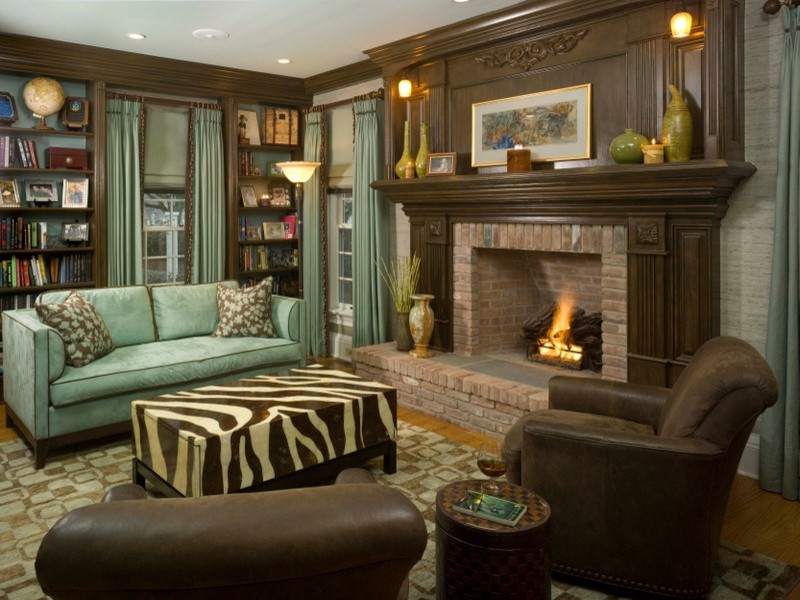 Photo of a mid-sized eclectic enclosed family room in New York with a library, grey walls, light hardwood floors, a standard fireplace, a brick fireplace surround, no tv and brown floor.