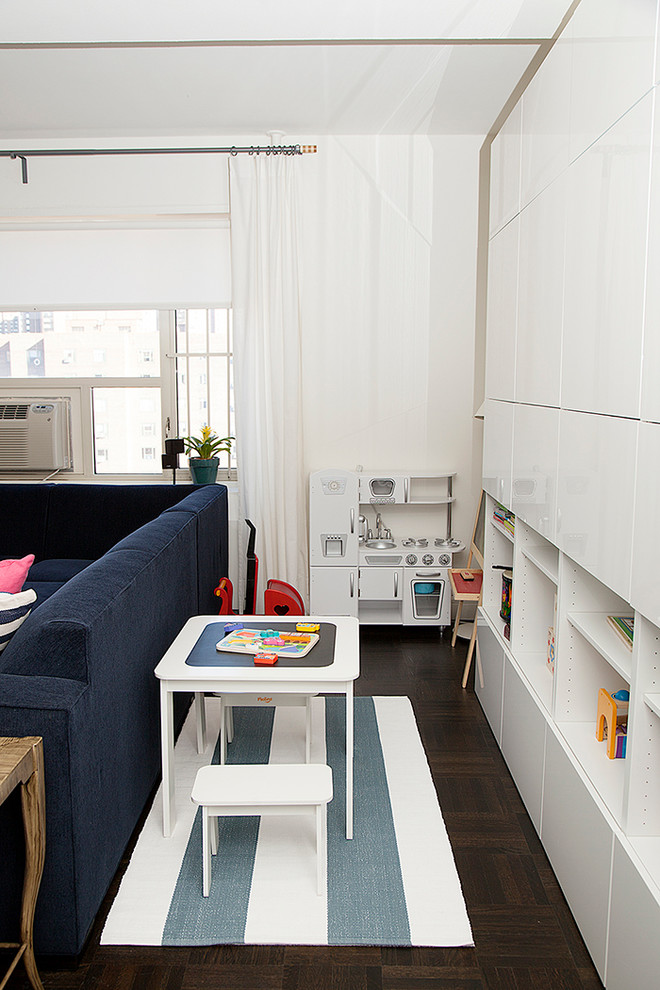 Contemporary gender-neutral kids' playroom in New York with white walls and dark hardwood floors.