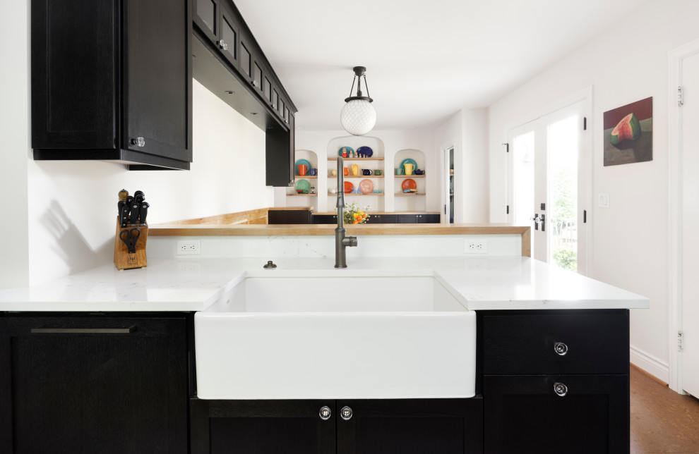 This is an example of a large galley eat-in kitchen in Portland with a farmhouse sink, shaker cabinets, black cabinets, quartz benchtops, multi-coloured splashback, terra-cotta splashback, black appliances, cork floors, no island, brown floor and white benchtop.