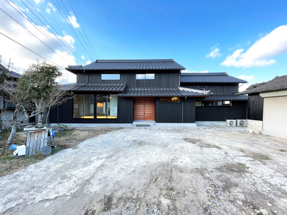 Mid-sized two-storey black house exterior in Fukuoka with wood siding, a gable roof, a mixed roof, a black roof and shingle siding.