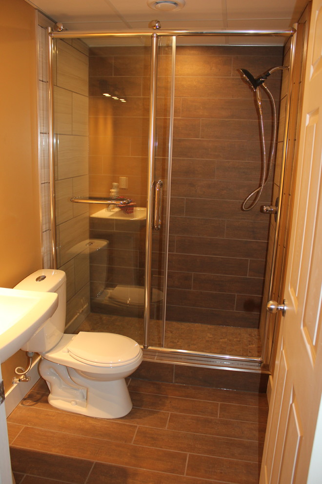 Mid-sized contemporary bathroom in Edmonton with an alcove shower, a two-piece toilet, brown tile, porcelain tile, beige walls, porcelain floors and a pedestal sink.