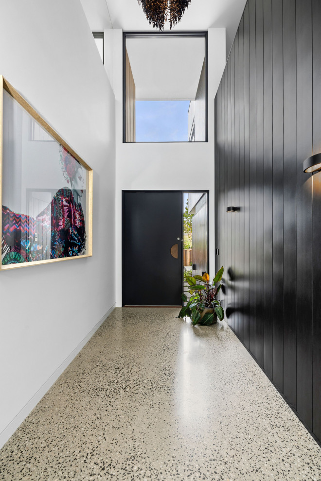 This is an example of a large contemporary front door in Geelong with black walls, concrete flooring, a single front door, a black front door and wainscoting.