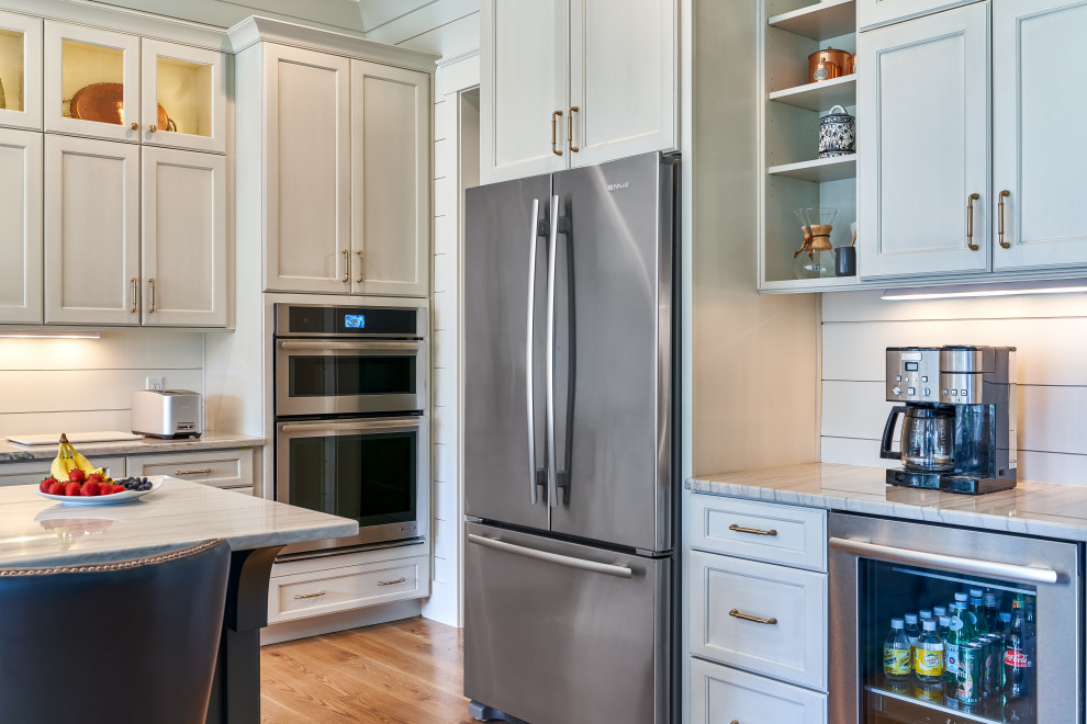Open concept kitchen - large transitional l-shaped light wood floor and brown floor open concept kitchen idea with a farmhouse sink, flat-panel cabinets, gray cabinets, granite countertops, white backsplash, wood backsplash, stainless steel appliances, an island and white countertops