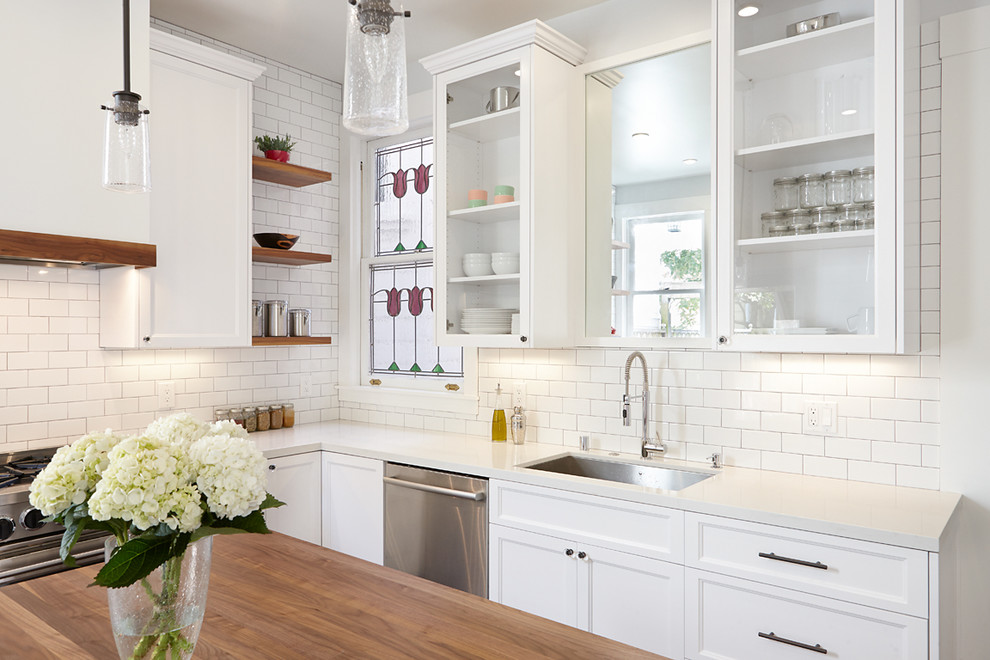Design ideas for a mid-sized traditional l-shaped eat-in kitchen in San Francisco with a single-bowl sink, shaker cabinets, white cabinets, quartz benchtops, white splashback, subway tile splashback, stainless steel appliances, dark hardwood floors and with island.