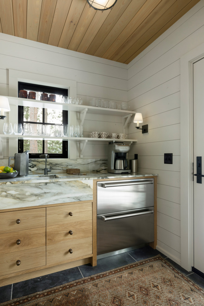 Wet bar - rustic single-wall black floor wet bar idea in Minneapolis with an undermount sink, flat-panel cabinets, light wood cabinets, marble countertops, white backsplash, marble backsplash and white countertops