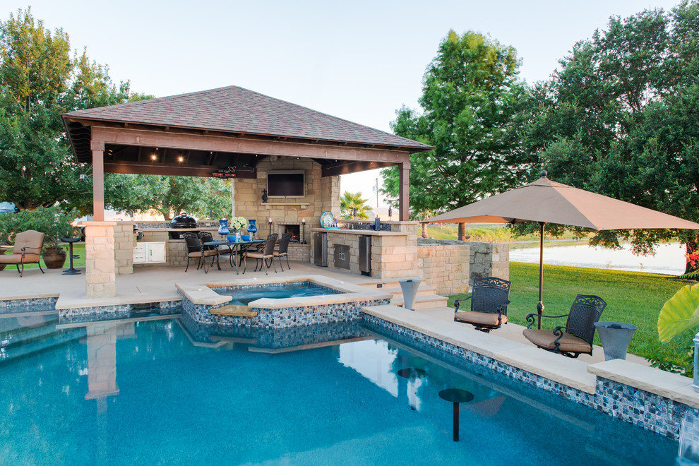 Photo of a mid-sized traditional backyard custom-shaped pool in Austin with a hot tub and stamped concrete.