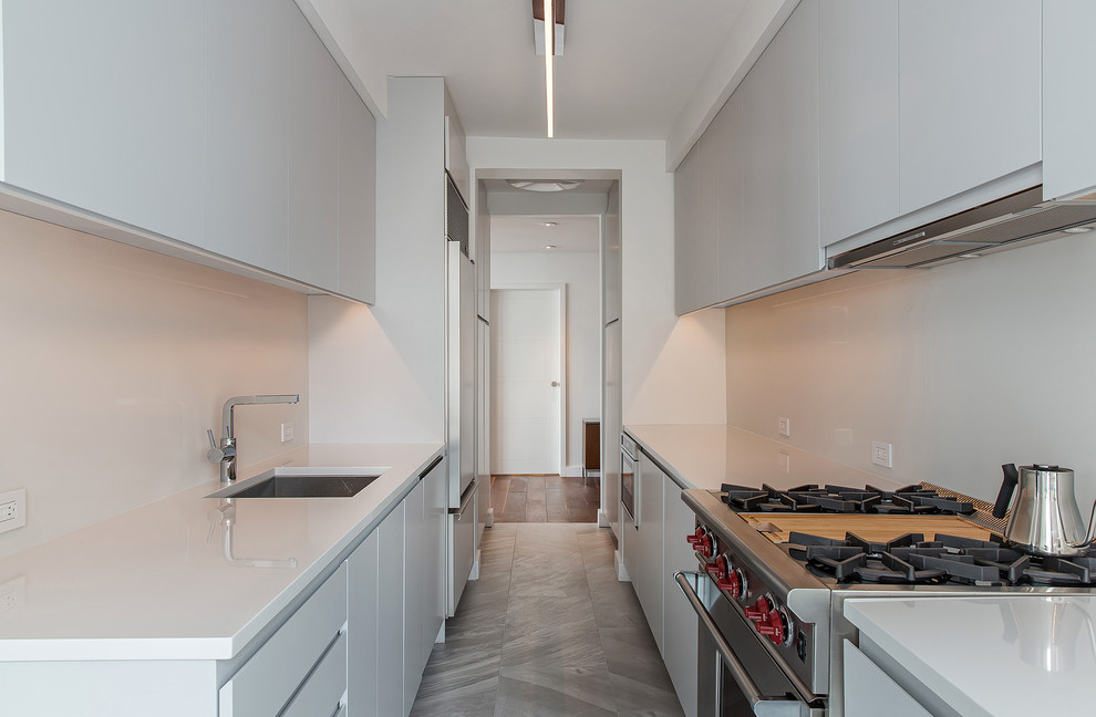 This is an example of a small contemporary single-wall separate kitchen in New York with an undermount sink, flat-panel cabinets, white cabinets, solid surface benchtops, stainless steel appliances, slate floors and no island.
