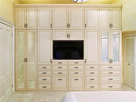 This is an example of a large traditional women's walk-in wardrobe in Miami with raised-panel cabinets, beige cabinets, carpet and beige floor.