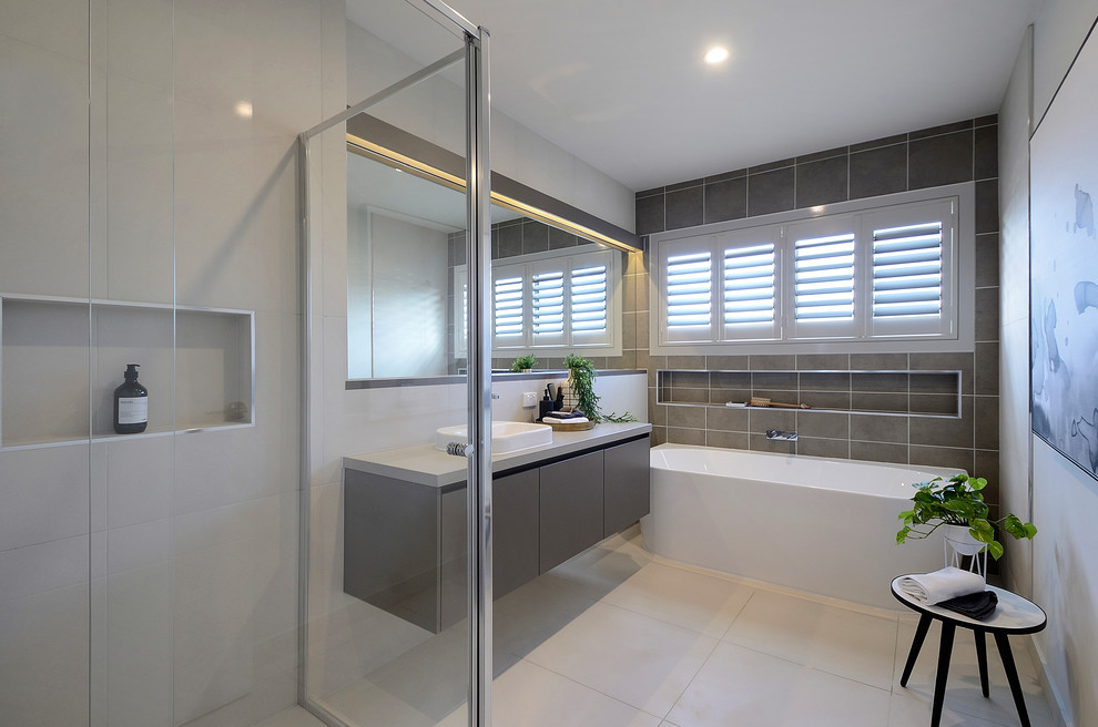 Design ideas for a mid-sized contemporary kids bathroom in Melbourne with flat-panel cabinets, brown cabinets, a freestanding tub, a corner shower, a one-piece toilet, beige tile, ceramic tile, white walls, ceramic floors, a vessel sink, engineered quartz benchtops, beige floor, a hinged shower door and beige benchtops.