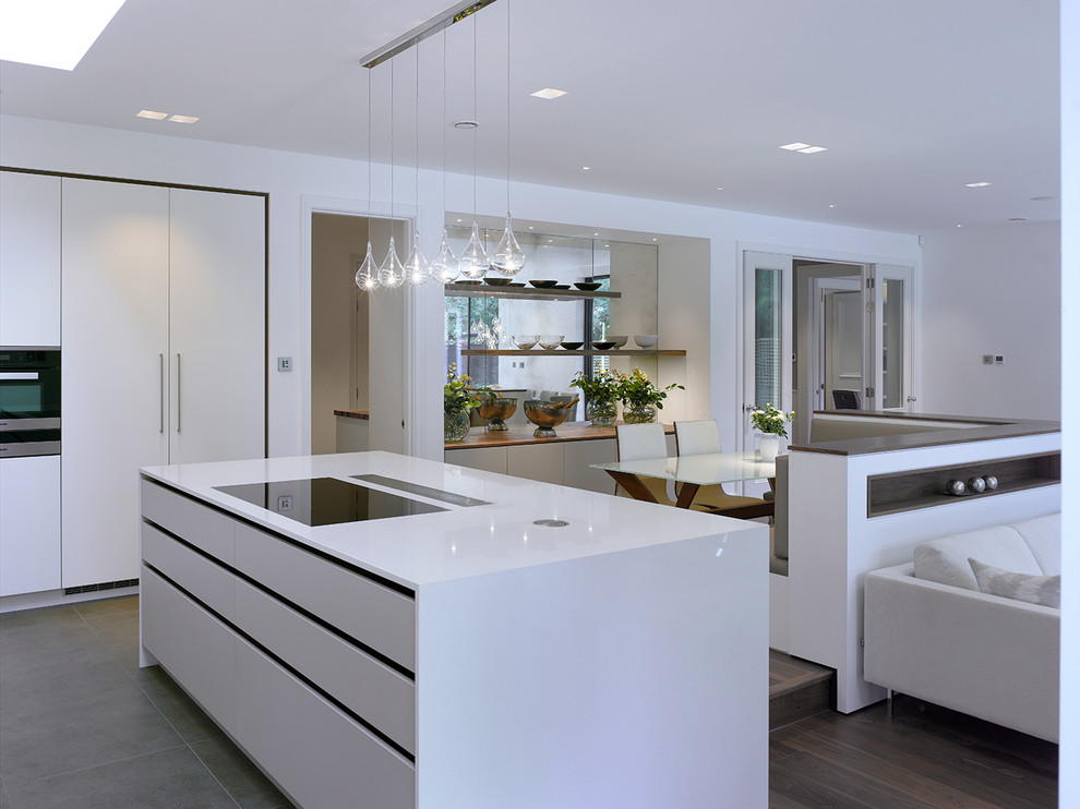 Design ideas for an expansive contemporary open plan kitchen in London with flat-panel cabinets, white cabinets, solid surface benchtops, beige splashback, glass sheet splashback, with island and white benchtop.