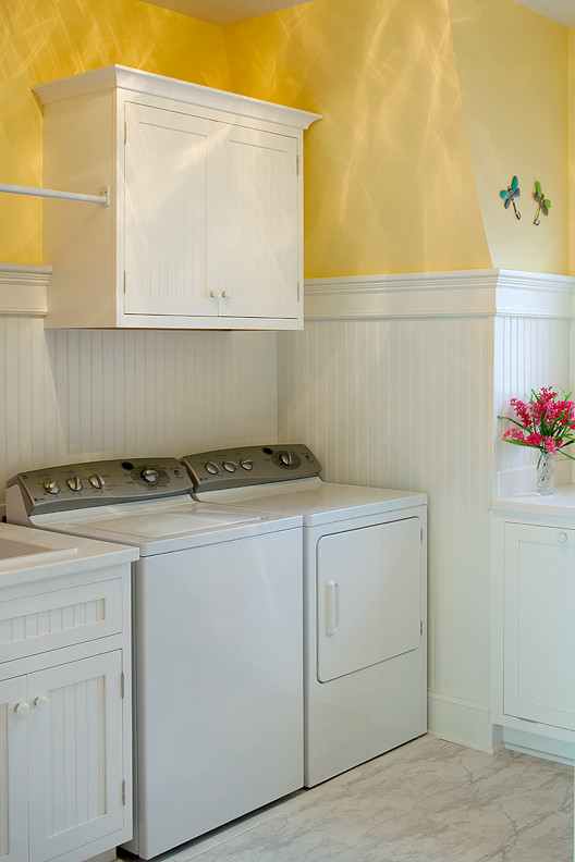 Photo of a large traditional single-wall utility room in Grand Rapids with recessed-panel cabinets, white cabinets, yellow walls and a side-by-side washer and dryer.