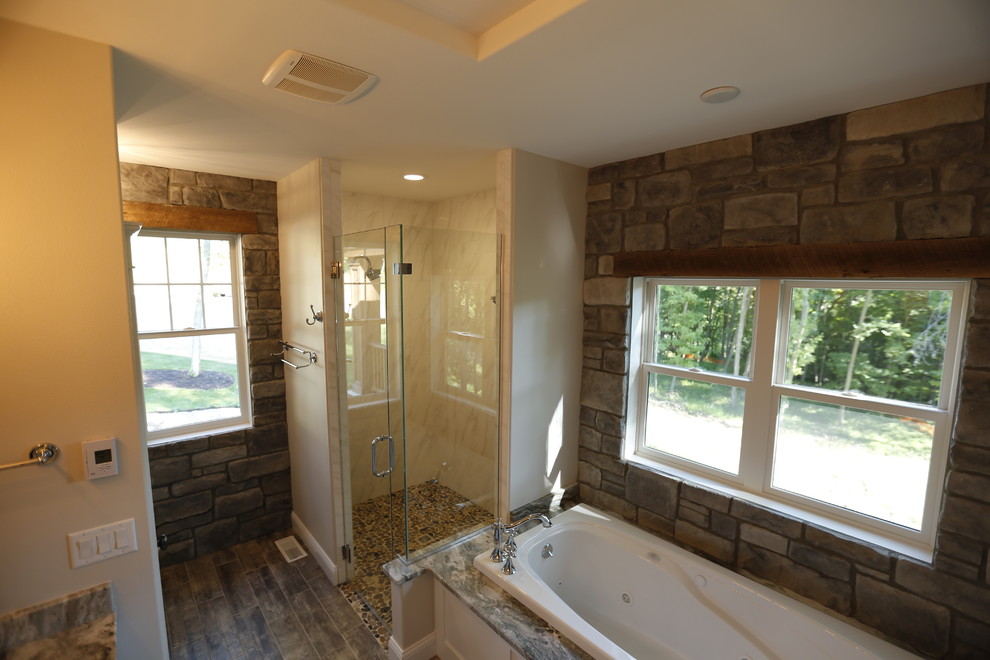 Photo of a mid-sized country master bathroom in Cedar Rapids with shaker cabinets, white cabinets, a drop-in tub, a corner shower, a one-piece toilet, brown tile, ceramic tile, beige walls, ceramic floors, an undermount sink and marble benchtops.