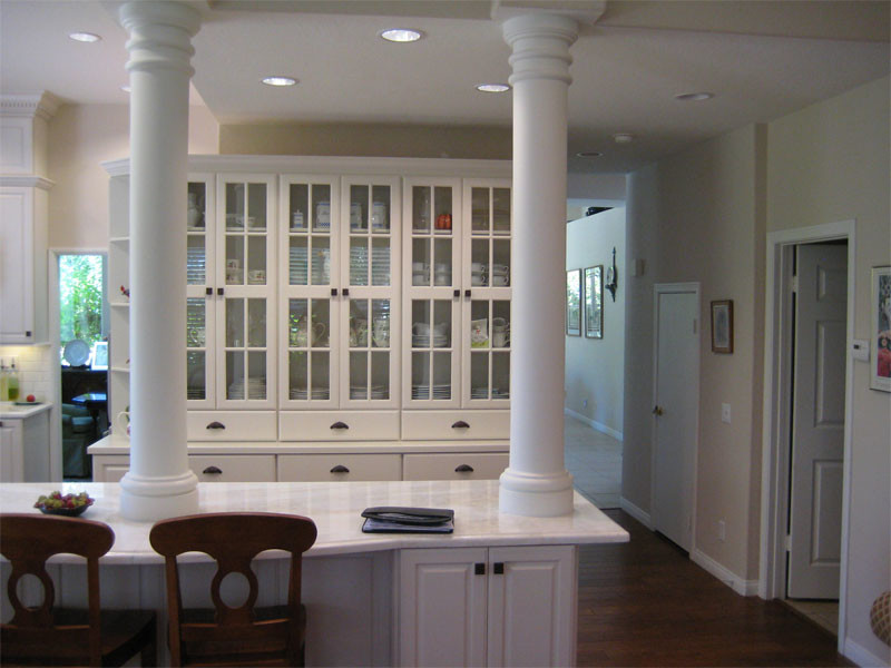 Inspiration for a mid-sized transitional u-shaped brown floor and dark wood floor enclosed kitchen remodel in Orange County with an undermount sink, raised-panel cabinets, white cabinets, solid surface countertops, white backsplash, subway tile backsplash, stainless steel appliances and an island