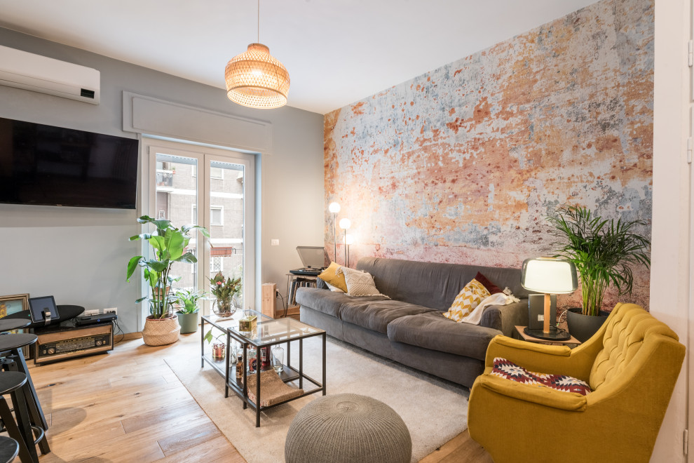 Ejemplo de salón actual con paredes multicolor, suelo de madera clara, televisor colgado en la pared, suelo beige y papel pintado