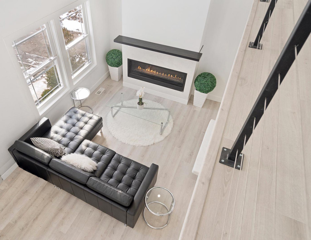 Modern Residential Construction - Large minimalist formal and loft-style light wood floor, brown floor, vaulted ceiling and wall paneling living room photo in Newark with white walls, a standard fireplace, a wood fireplace surround and a wall-mounted tv