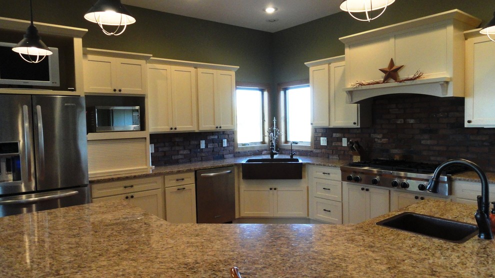 Example of a large transitional l-shaped dark wood floor and brown floor open concept kitchen design with a farmhouse sink, white cabinets, granite countertops, stainless steel appliances, green walls, an island, shaker cabinets, brown backsplash and stone tile backsplash