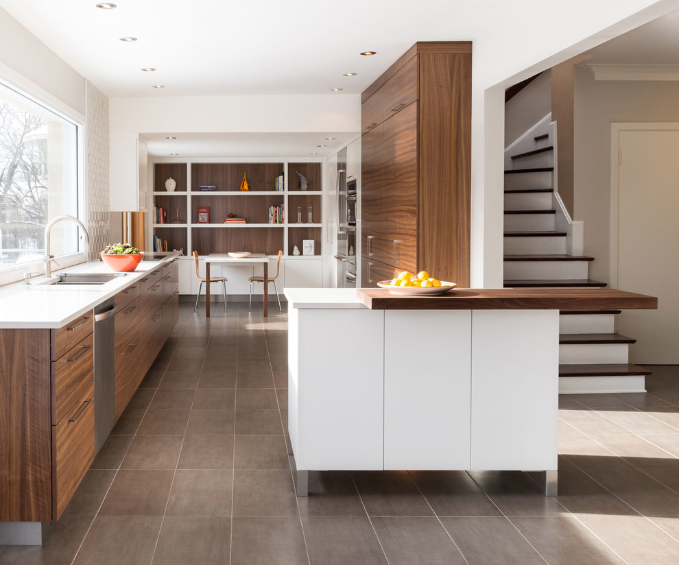 Design ideas for a mid-sized contemporary u-shaped eat-in kitchen in Montreal with a double-bowl sink, flat-panel cabinets, stainless steel appliances, medium wood cabinets, quartz benchtops, white splashback, stone tile splashback, porcelain floors and with island.