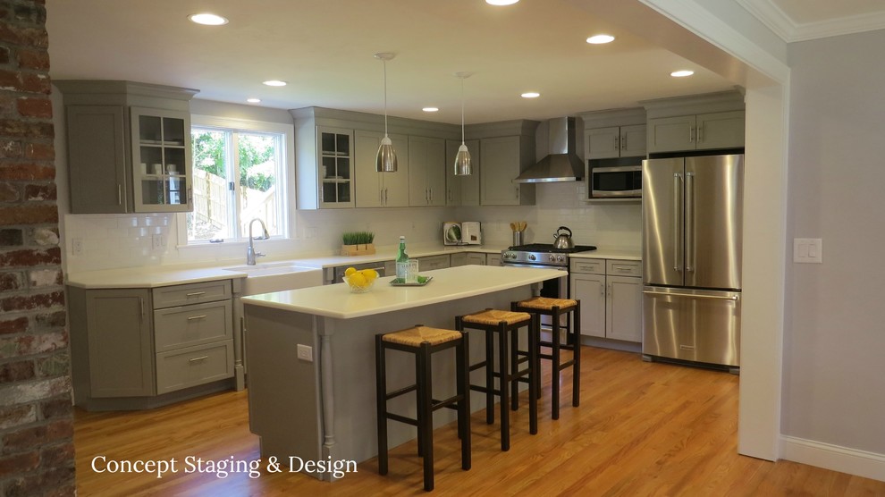 Kitchen - transitional medium tone wood floor kitchen idea with a farmhouse sink, shaker cabinets, gray cabinets, white backsplash, stainless steel appliances and an island