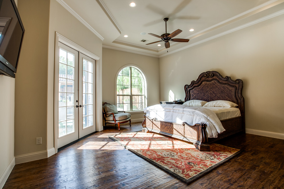 Large mediterranean guest bedroom in Austin with beige walls, medium hardwood floors, a standard fireplace and a stone fireplace surround.