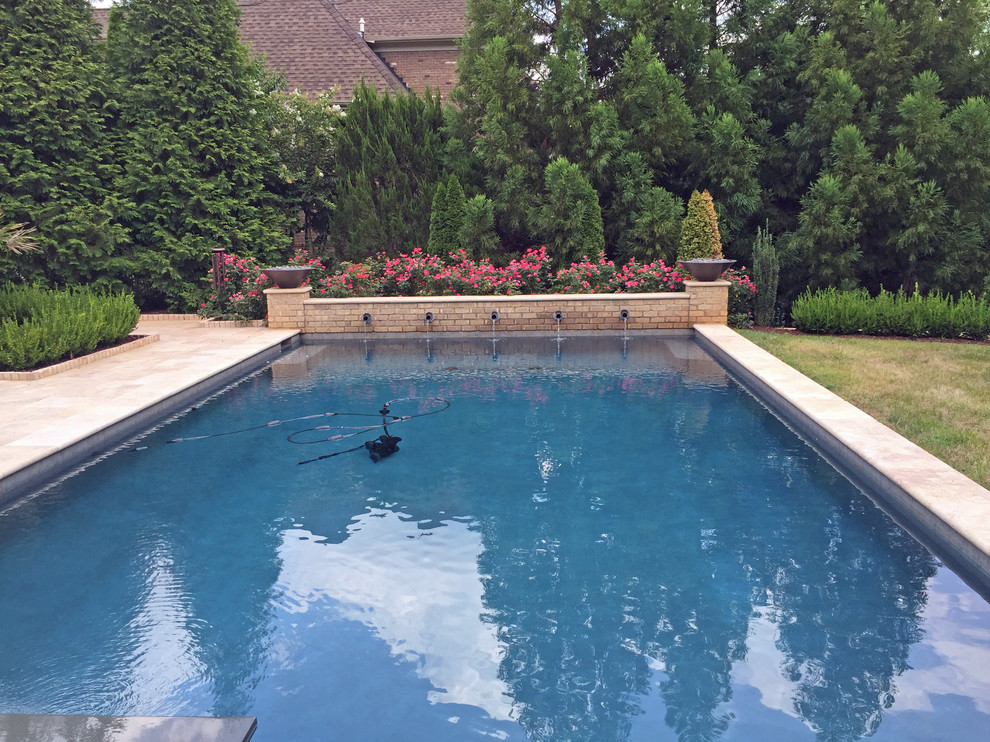 На фото: большой естественный, прямоугольный бассейн на заднем дворе в стиле неоклассика (современная классика) с джакузи и покрытием из каменной брусчатки с