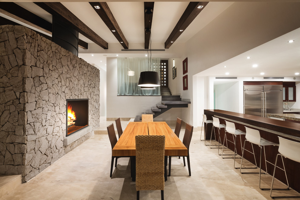 Photo of a mid-sized contemporary open plan dining in Other with white walls, marble floors, a two-sided fireplace, a metal fireplace surround and beige floor.