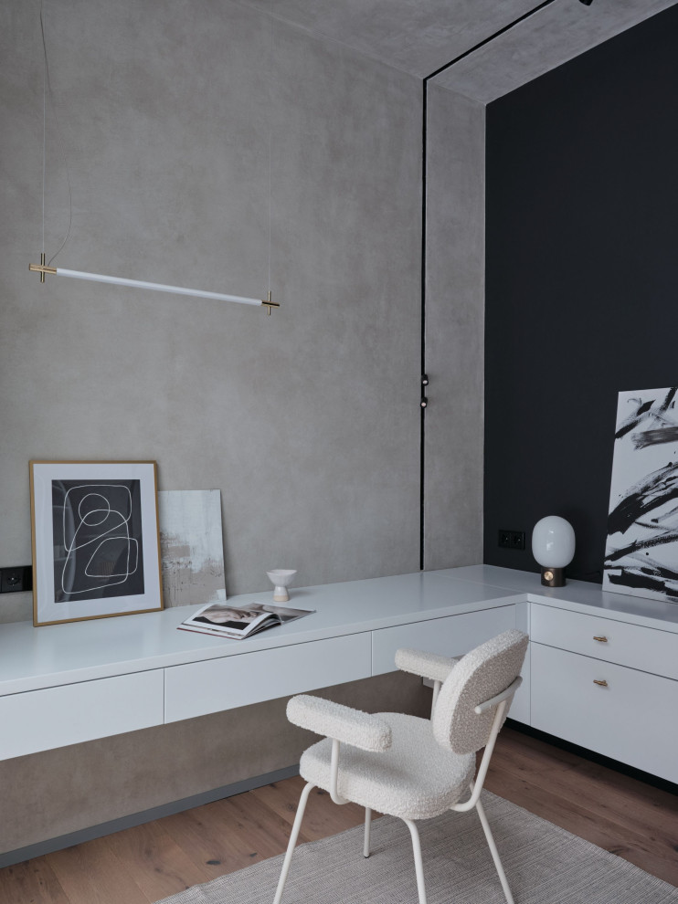 Imagen de despacho moderno grande con paredes grises, suelo de madera clara, escritorio empotrado y suelo marrón