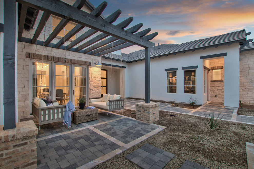 Country backyard patio in Phoenix with concrete pavers and a pergola.