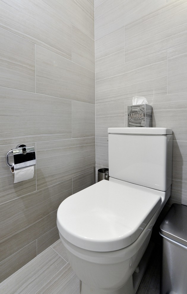 Mid-sized contemporary powder room in New York with an integrated sink, flat-panel cabinets, black cabinets, solid surface benchtops, a two-piece toilet, gray tile and beige walls.