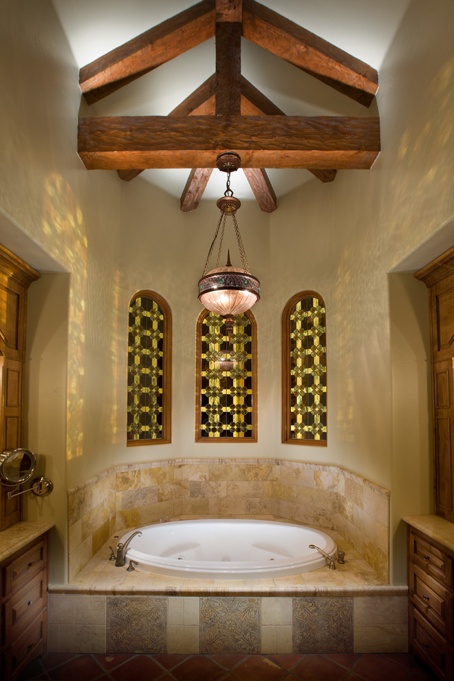 Design ideas for a mediterranean master bathroom in San Diego with raised-panel cabinets, medium wood cabinets, a drop-in tub, beige tile and beige walls.