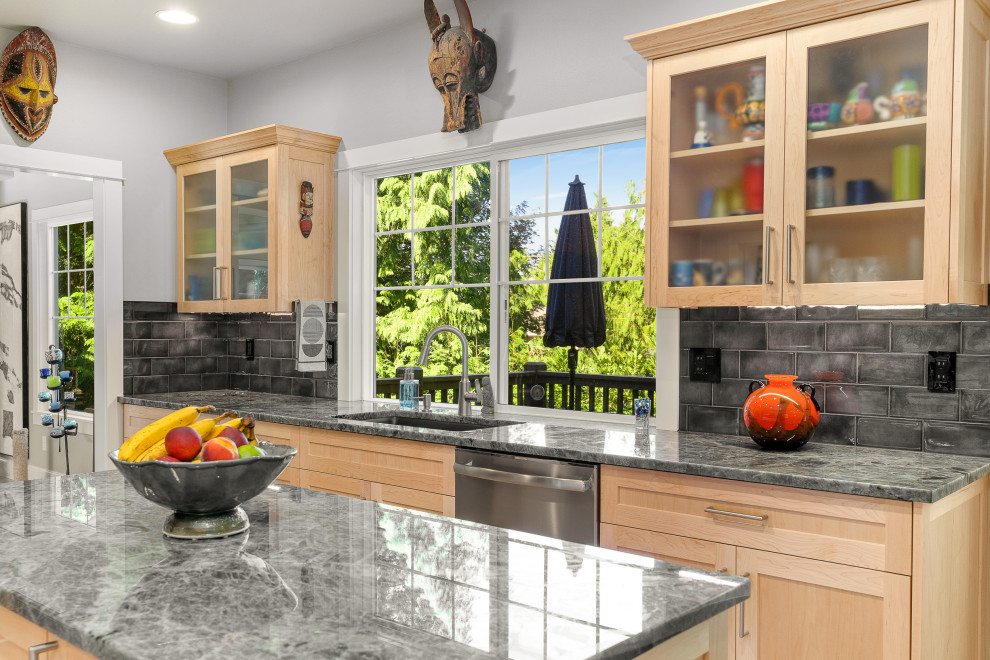 Design ideas for a large transitional galley open plan kitchen in Seattle with an undermount sink, shaker cabinets, light wood cabinets, granite benchtops, black splashback, subway tile splashback, stainless steel appliances, light hardwood floors, with island, beige floor and grey benchtop.
