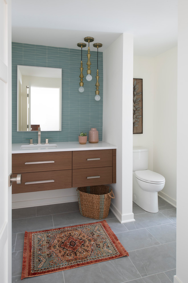 This is an example of a mid-sized midcentury 3/4 bathroom in Minneapolis with flat-panel cabinets, medium wood cabinets, white tile, white walls, porcelain floors, an undermount sink, engineered quartz benchtops, grey floor and white benchtops.