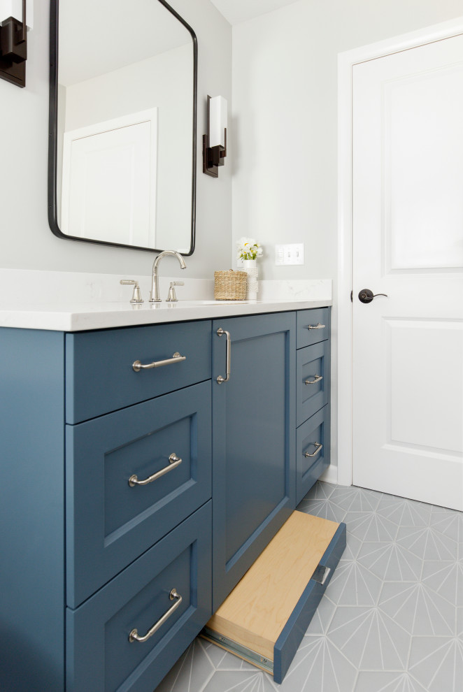 Mid-sized transitional kids bathroom in Portland with recessed-panel cabinets, blue cabinets, an alcove tub, an alcove shower, white tile, ceramic tile, engineered quartz benchtops, white benchtops, a single vanity, a built-in vanity, a two-piece toilet, grey walls, porcelain floors, an undermount sink, grey floor, a sliding shower screen and a niche.