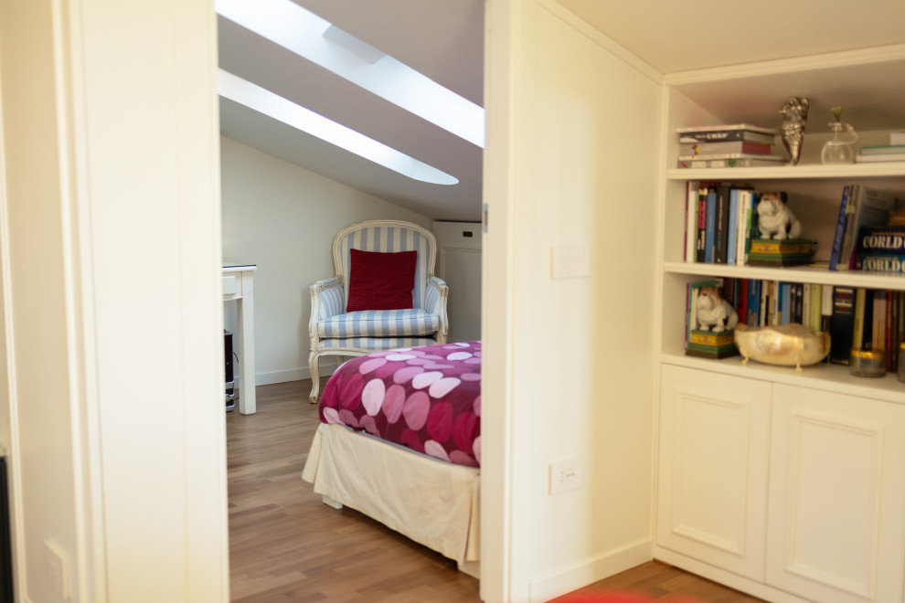 Ejemplo de habitación de niña tradicional pequeña con escritorio, paredes blancas, suelo de madera clara y suelo marrón