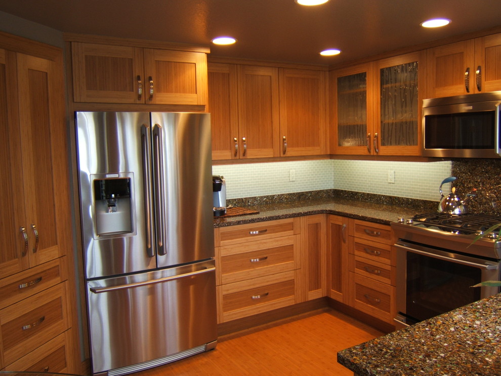 This is an example of a mid-sized contemporary u-shaped eat-in kitchen in Orange County with an undermount sink, raised-panel cabinets, light wood cabinets, recycled glass benchtops, glass tile splashback, stainless steel appliances, bamboo floors and no island.