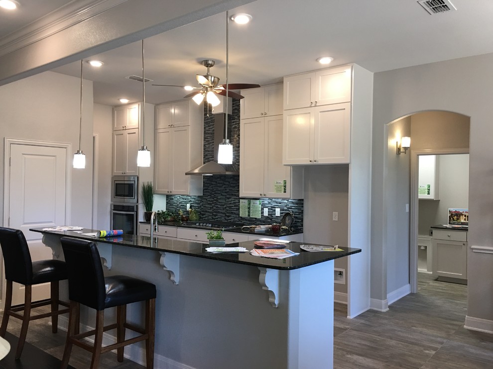 Inspiration for a mid-sized contemporary single-wall eat-in kitchen in Austin with shaker cabinets, stainless steel cabinets, granite benchtops, multi-coloured splashback, matchstick tile splashback, stainless steel appliances, porcelain floors, with island and brown floor.