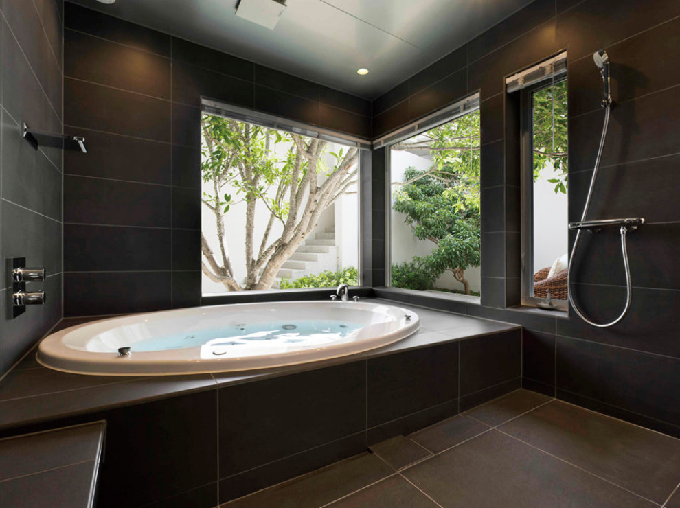 Photo of a modern bathroom in Tokyo with a built-in bath, black tiles, black walls, black floors and a drop ceiling.